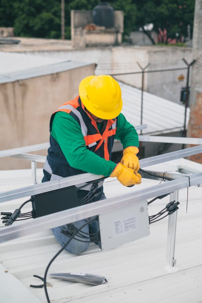 Electrician with PPE working on rooftop solar panel installation, focusing on safety.